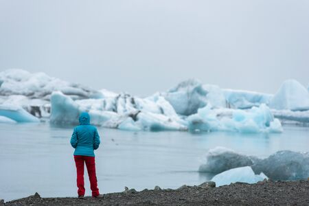 Tourist admiring the melting icebergs floating in Jokulsarlon glacial lagoon, as a result of global warming and climate change. Vatnajokull National Park, Icelandの写真素材