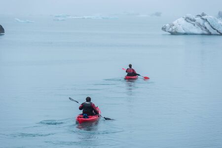 JOKULSARLON, ICELAND - MAY 22, 2019: Man paddling in a kayak in the freezing waters of Jokulsarlon glacier lagoon between icebergsのeditorial素材