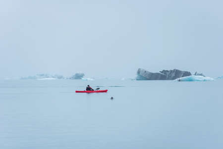 JOKULSARLON, ICELAND - MAY 22, 2019: Man paddling in a kayak in the freezing waters of Jokulsarlon glacier lagoon between icebergsのeditorial素材