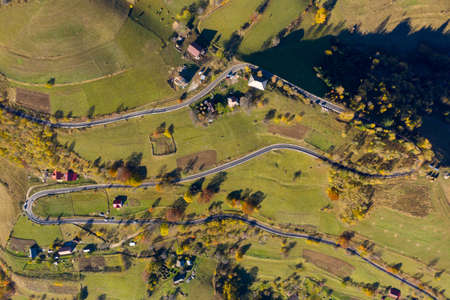 Aerial view of epic countryside road and autumn forest from above, drone point of view