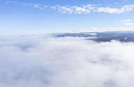 Aerial drone shot of flying above clouds in a misty morning