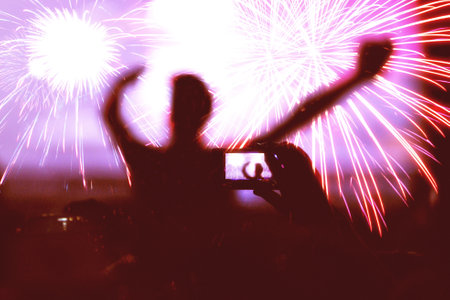 Rear view of crowd with arms outstretched watching fireworks. New Year conceptの写真素材