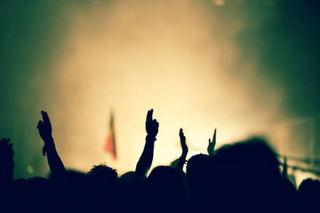 Silhouette of hands on a concert in front of bright stage lightsの写真素材