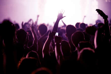 Crowd of people celebrating the New Year's Eve at a party. Stage lights in the backgroundの写真素材