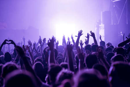 Crowd of people celebrating the New Year's Eve at a party. Stage lights in the backgroundの写真素材