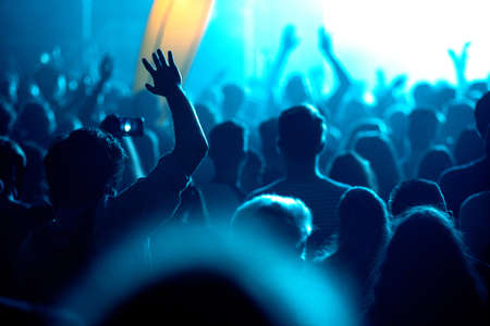 Crowd of people celebrating the New Year's Eve at a party. Stage lights in the background