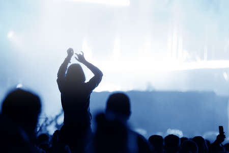 Rear view of silhouette of crowd with arms outstretched at concert. Summer music festival conceptの写真素材
