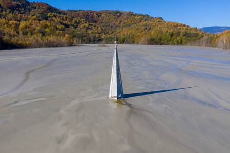 Abstract aerial view of church tower with cross and shadow, flooded by copper mining residuals and mud. Geamana, Romania. Industrial and religion conceptの写真素材