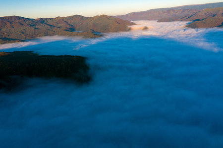 Aerial view of morning fog in the valley in dawn. Above the cloudsの写真素材