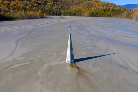 Aerial view of a church tower with cross, buried under mud and mining residuals. Apocalyptic scene in Transylvania, Romaniaの写真素材