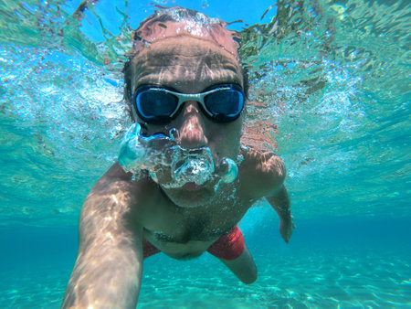 Swimmer man taking an underwater selfie in tropical sea waterの写真素材