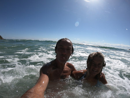 Powerful ocean waves splashing funny couple. Summer vacation conceptの写真素材