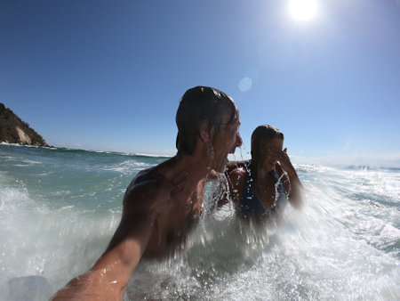 Ocean waves splashing on a romantic couple. Summer honeymoon conceptの写真素材