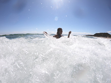Powerful sea waves splashing on a cheerful woman bodyの写真素材