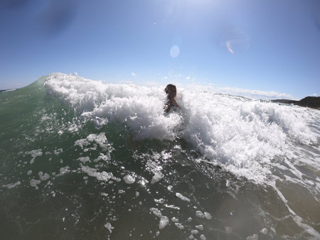 Powerful sea waves splashing on a cheerful woman bodyの写真素材