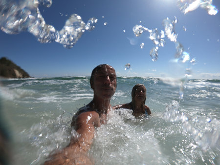 Powerful ocean waves splashing funny couple. Summer vacation conceptの写真素材