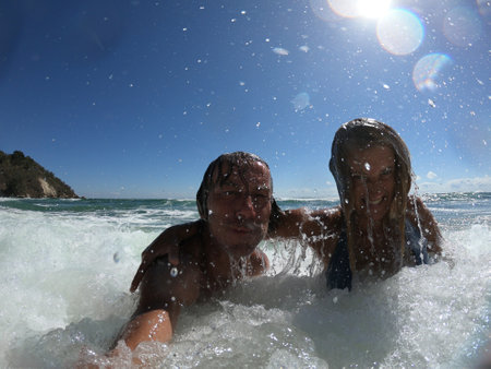 Powerful ocean waves splashing funny couple. Summer vacation conceptの写真素材