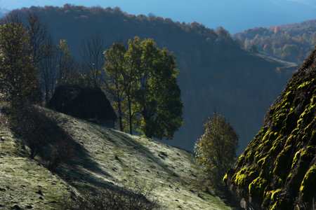 Autumn countryside landscape with wooden houses, thatched roof during sunriseの写真素材