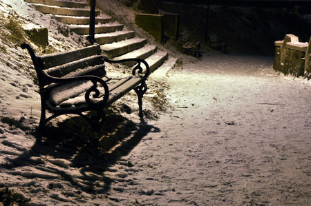 Snow covered empty bench in the winter at nightの写真素材