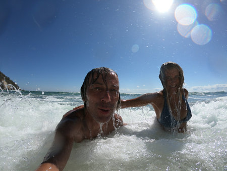 Ocean waves splashing on a romantic couple. Summer honeymoon conceptの写真素材