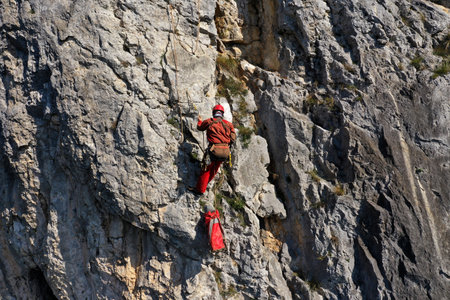 Aerial view of mountain rescuer doing rescue operations hanging on a ropeの写真素材