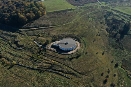 Aerial view of big concrete water tank reservoir in the meadow by drone