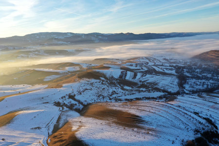 Aerial view of sunset over misty winter mountains by droneの写真素材