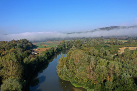 Aerial view of quiet river and forest in a misty morning by droneの写真素材