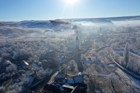Morning sunrise lights and mist, fog over village church tower aerial drone viewの写真素材