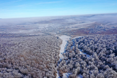 Flying over frosty winter hills and forest by droneの写真素材