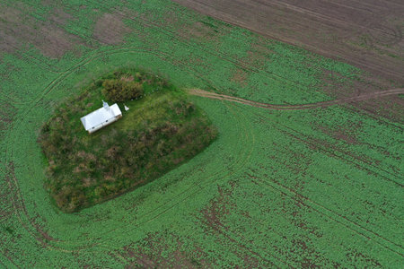 Aerial view of small white chapel in the middle of agricultural field by droneの写真素材