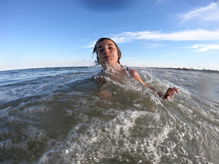 Powerful ocean waves splashing on child girl. Summer vacation conceptの写真素材