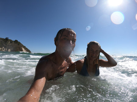 Powerful ocean waves splashing funny couple. Summer vacation conceptの写真素材