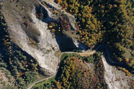Aerial top down view of deep canyon, gorge road in autumn forest by droneの写真素材
