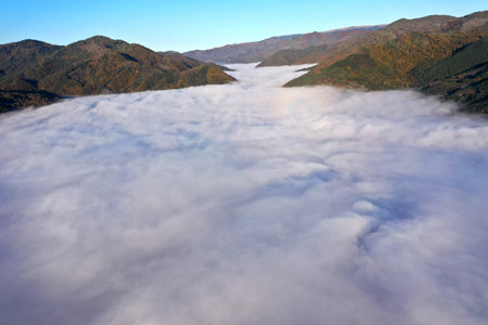 Aerial view of autumn morning mist and clouds in the valley by droneの写真素材