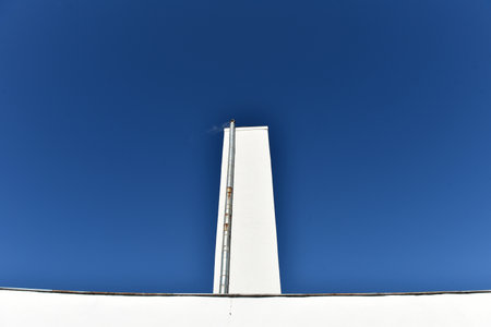 Industrial whitewashed chimney tower against blue skyの写真素材