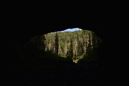 Cave entrance silhouette from inside. Mysterious view from undergroundの写真素材