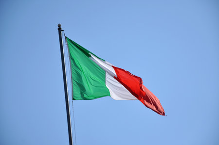 Flag of Italy waving against blue skyの写真素材