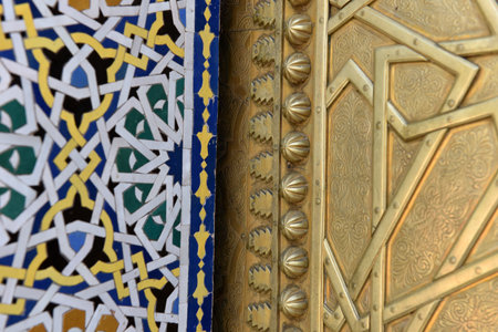 Golden brass door with Arabic calligraphy and Moroccan zellij mosaic tilework. Royal Palace, Fez,...