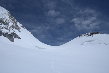 A stunning rock formation covered in snow, set against a clear blue sky with fluffy clouds in the...