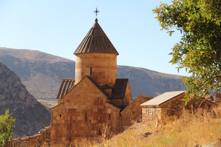 Stone church in a mountainous landscape with a round dome and cross on top. Historical architecture and religious heritage concept.の写真素材