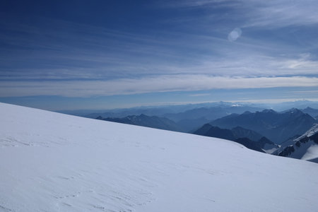 A stunning rock formation covered in snow, set against a clear blue sky with fluffy clouds in the background, creating a peaceful and breathtaking mountain landscape.の写真素材