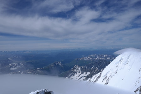 A stunning rock formation covered in snow, set against a clear blue sky with fluffy clouds in the background, creating a peaceful and breathtaking mountain landscape.の写真素材