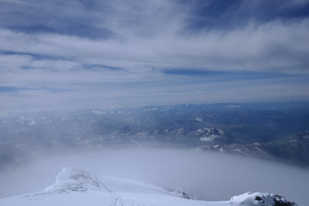 A stunning rock formation covered in snow, set against a clear blue sky with fluffy clouds in the background, creating a peaceful and breathtaking mountain landscape.の写真素材