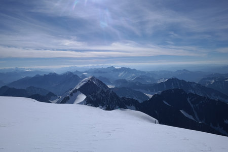 A stunning rock formation covered in snow, set against a clear blue sky with fluffy clouds in the...