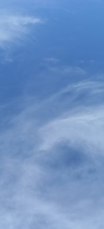 Capture the serene beauty of a blue sky adorned with soft clouds. This image evokes calmness and tranquility, ideal for backgrounds or creative projects needing an airy, natural touch.の写真素材