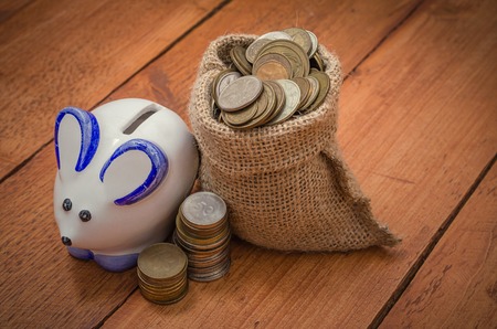 The concept Piggy bank and coins on wooden background. Savings, savings, investments.の写真素材