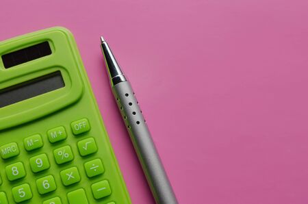 The calculation of the budget, taxes and the cost of the calculator on a pink background. Top view of calculator with pen .の写真素材