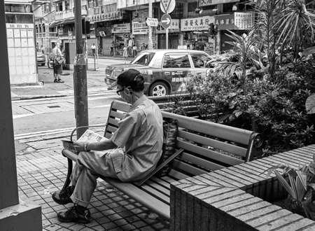 Hong Kong, Sep 5,2019 : Senior man sitting on park bench reading newspaper.のeditorial素材