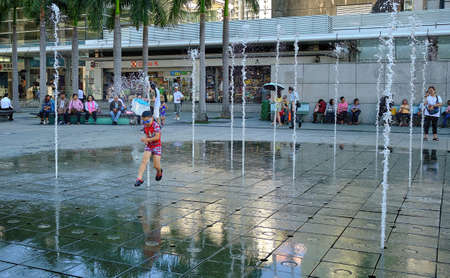 Happy children playing between water jets in water fountain. Fountains near Citygate Outlets.のeditorial素材